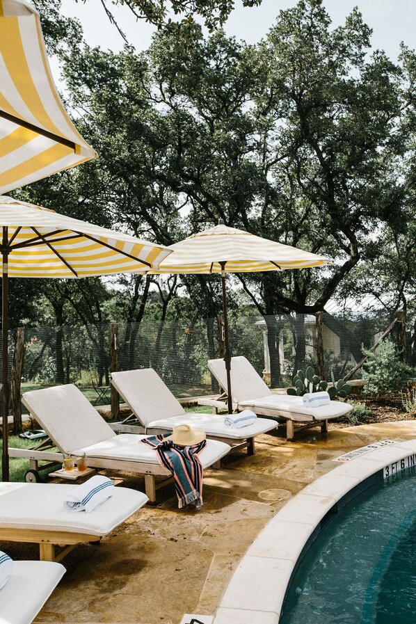 A poolside area with lounge chairs and striped umbrellas.