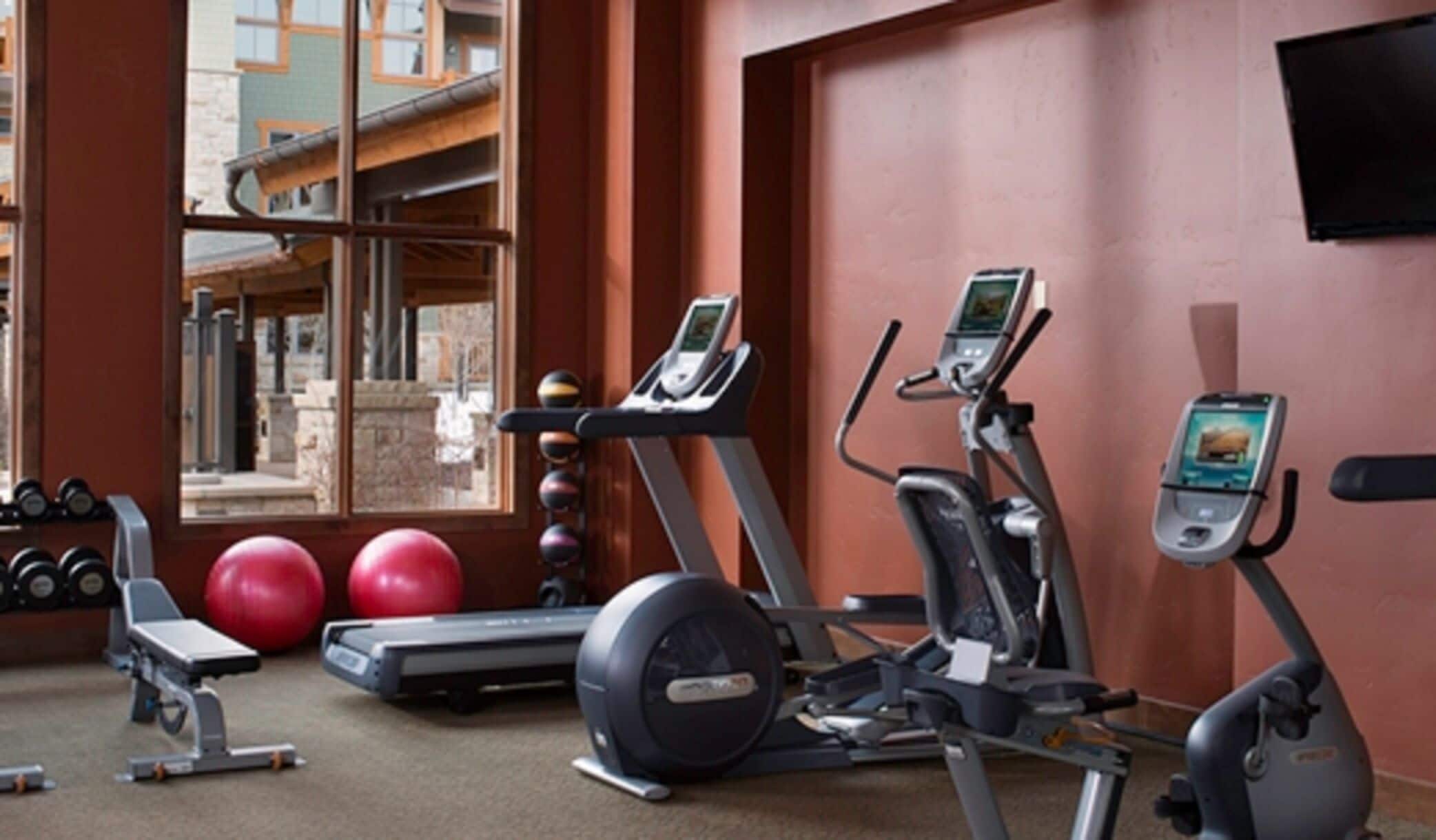 Een fitnessruimte met loopbanden, elliptische trainers en fitnessballen.