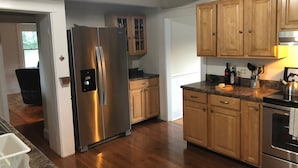 Eine Küche mit Holzschränken, einem Edelstahlkühlschrank, einer Granitarbeitsplatte und einem eingebauten Backofen.