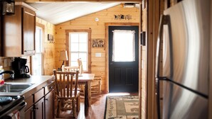 L’intérieur de la cabane est doté de murs en bois, d’un coin repas avec une table et des chaises, d’une cuisine équipée d’une cuisinière et d’une machine à café, ainsi que d’un réfrigérateur.
