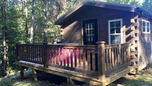 Une cabane dotée d’une terrasse en bois et d’un petit porche.
