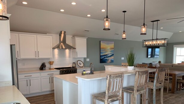 A modern kitchen with white cabinets, a large island with bar stools, and pendant lighting. - Steps to Beach*Private Heated Pool*Elevator* Jennette's Pier (Nags Head)