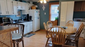 A kitchen with white cabinets, a dining table with chairs, and a ceiling fan. - Relaxing Gem Beach, Close to Twin Oast Brewery, Orchard Eatery and Miller Ferry (Port Clinton)