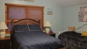 A bedroom with a wooden bed, a ceiling fan, a nightstand with a lamp, and a small table with a clock. - Relaxing Gem Beach, Close to Twin Oast Brewery, Orchard Eatery and Miller Ferry (Port Clinton)