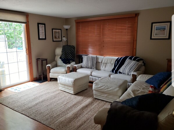 A living room with a beige sofa, a white armchair, and a coffee table. There is a window with blinds, a lamp, and framed pictures on the wall. - Relaxing Gem Beach, Close to Twin Oast Brewery, Orchard Eatery and Miller Ferry (Port Clinton)