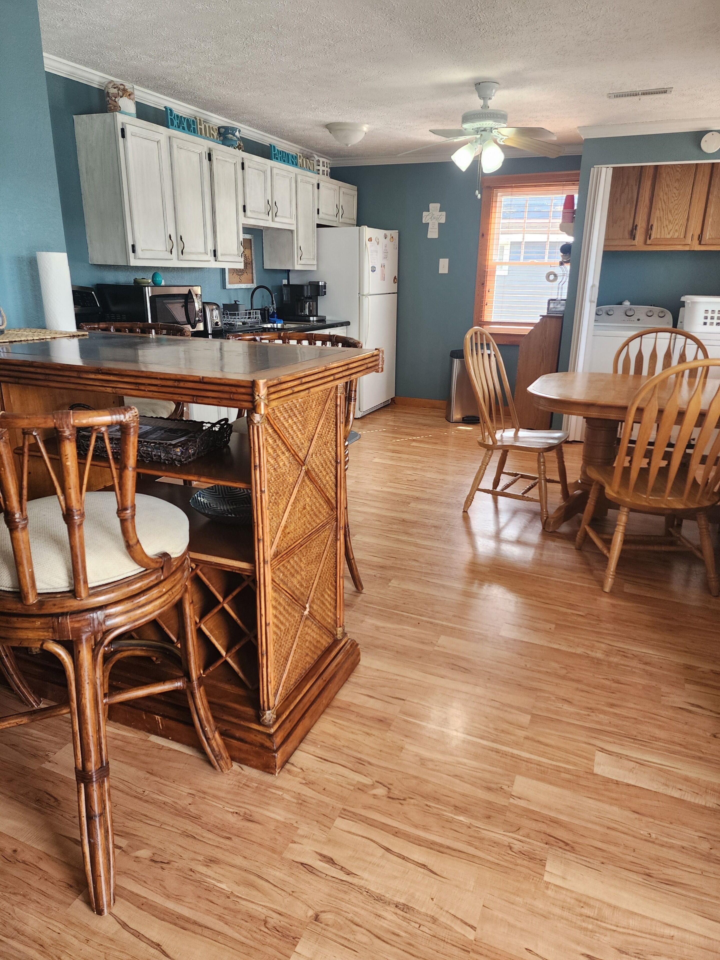A kitchen with wooden cabinets, a dining table with chairs, and a ceiling fan.