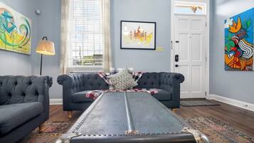 Een woonkamer met twee donkere banken, een kamerkleed met patroon, een metalen tafel en kunstwerken aan de muur.