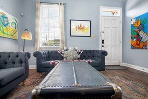 A living room with two dark sofas, a patterned rug, a metal table, and artwork on the walls.