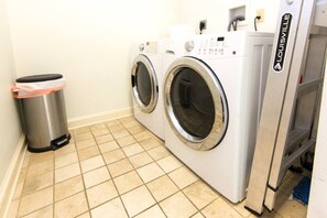Convenient laundry facilities feature two front-loading washing machines and a trash can.
