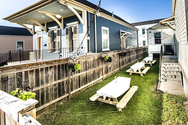 A backyard with a wooden deck, picnic tables, and a covered patio area.