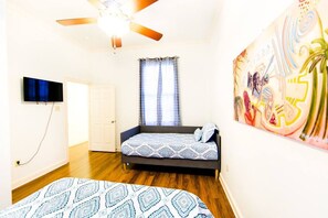 Cozy retreat with a single bed, ceiling fan, and vibrant artwork.