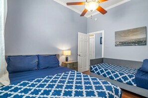 Une chambre à coucher avec un lit, une table de chevet, un ventilateur de plafond et une porte.
