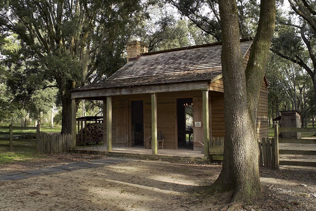 A rustic wooden building with a porch, surrounded by trees.
