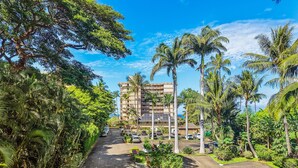 Un hôtel doté d’un parking, entouré d’une végétation luxuriante et de palmiers.