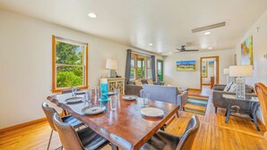 A dining area with a wooden table, chairs, and a view of greenery outside.