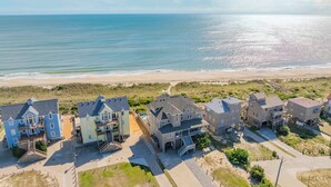 Un quartier résidentiel situé sur la côte, avec des maisons à proximité de la plage, caractérisé par un mélange de styles architecturaux et une vue dégagée sur l’océan.