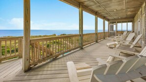 Une terrasse en bois avec des chaises de plage donnant sur l’océan.