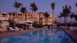 Un hotel con piscina, varios balcones y palmeras.
