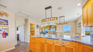 A spacious kitchen with wooden cabinets, a marble countertop, and a large island. - Oceanfront Avon Home with Private Pool, Hot Tub, Deluxe Game Room, Tiki Bar (Avon)
