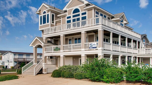 A multi-story beachfront house with a balcony, a staircase, and a sign indicating a beach view. - Semi-Oceanfront Home w/ Private Pool, Hot Tub, Elevator, Game Room, and Wet Bar (Salvo)