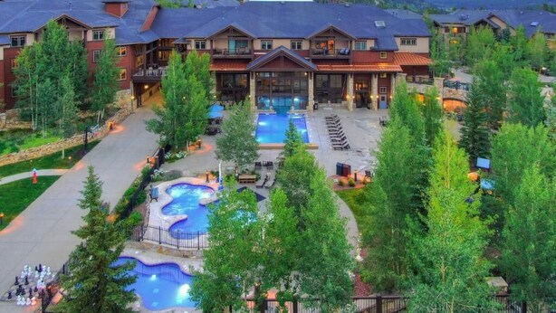 Ein Resort mit mehreren Gebäuden, einem zentralen Pool und einem kleineren Pool mit Liegestühlen darum.