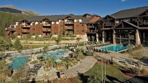 Ein Hotel mit mehreren Balkonen, einem Poolbereich und einer Bergkulisse.