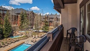 Ein Balkon mit Pool, Liegestühlen und Blick auf eine Wohngegend mit Häusern und Bäumen.