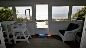 Una stanza con vista sull'oceano, una scrivania bianca, una sedia in vimini e un tappeto.