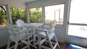 Un portico coperto con un tavolo bianco e quattro poltrone Adirondack.