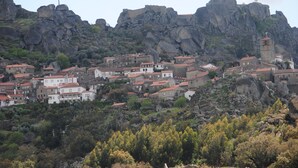 Un pueblo con edificios en una ladera, una torre destacada y terreno rocoso.