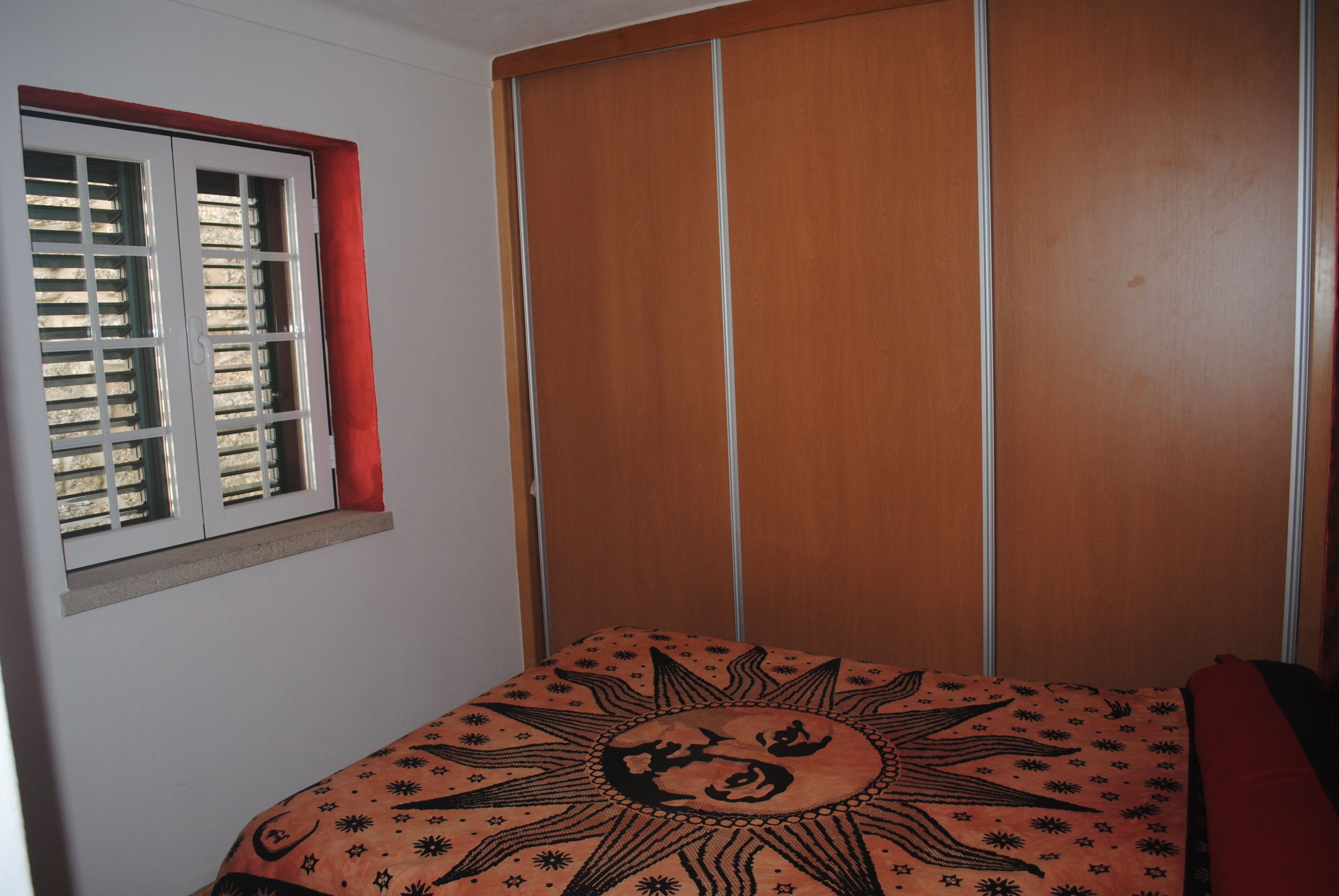 Una camera da letto con un letto, una finestra con persiane e un armadio.