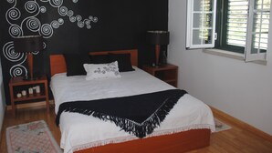 Un dormitorio con cama, dos mesitas de noche, una ventana con persianas y una pared con diseño en espiral.