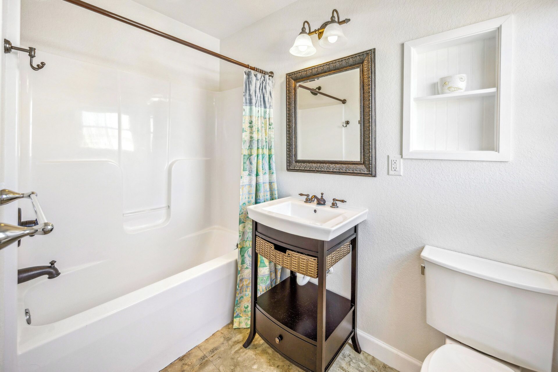 A bathroom with a bathtub, a sink with a mirror above it, and a toilet.