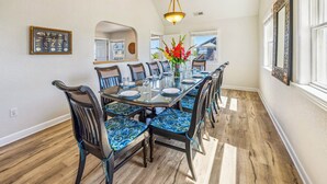 A dining area with a glass table, blue patterned chairs, and a vase of flowers. - Oceanview Home with Pool, Hot Tub, Game and Media Rooms. I Love Beach Music! (Salvo)