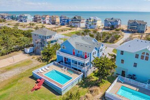 Un quartier résidentiel situé sur la côte, avec des maisons, une piscine et une plage.