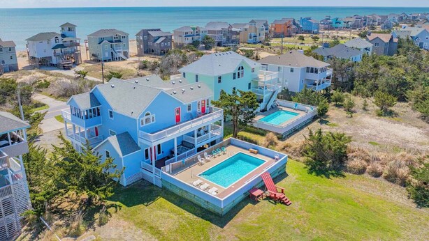 A coastal residential area with houses, a swimming pool, and a view of the ocean. - Semi-Oceanfront Home w/ Pool, Hot Tub, Elevator, Game Room, Home Theater (Avon)