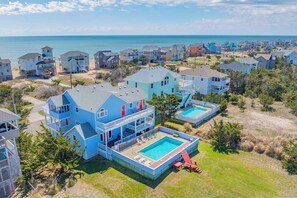 A coastal residential area with houses, a swimming pool, and a view of the ocean.