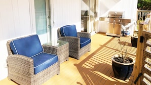 An outdoor patio with wicker furniture, a grill, and a potted plant.