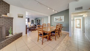 Un vaste espace dédié à la salle à manger, avec une cheminée en briques, une table à manger en bois et des chaises.
