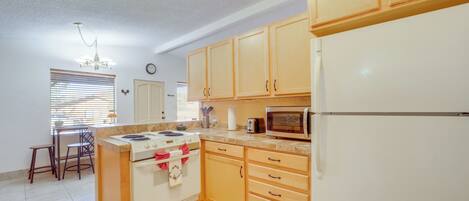 A kitchen with wooden cabinets, a white refrigerator, a microwave, a stove, and a sink.