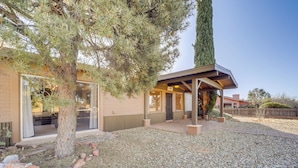 Une maison moderne dotée d’un patio couvert, d’une allée en gravier et d’un grand arbre.