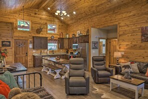 A log cabin interior with a dining area, kitchen, and seating space. - Relax Fireside: Family-Friendly Branson West Cabin (Branson West)