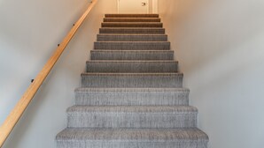 Una scala con gradini rivestiti di moquette e ringhiere in legno.