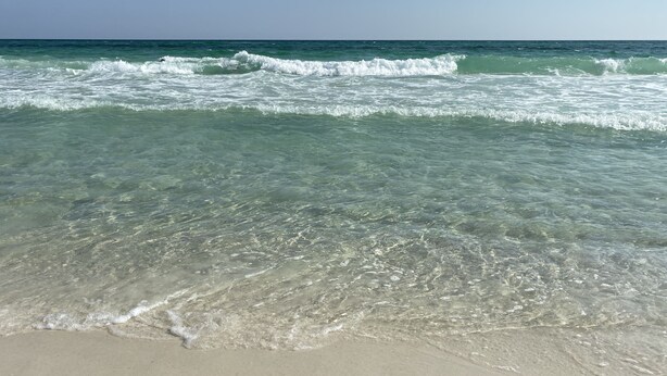 Een strand met helder water en golven.
