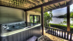 Un jacuzzi bajo una pérgola de madera con vista a un lago.
