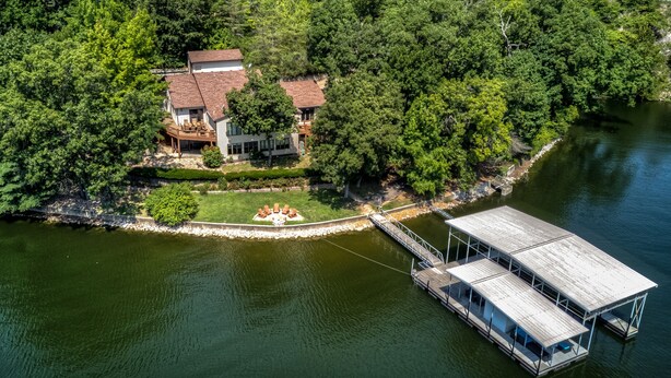 Vista aérea de una propiedad junto al lago con muelle, una casa con terraza y un rampa para embarcaciones.