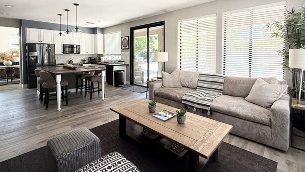 A modern kitchen with white cabinets, a black refrigerator, and a dining area with a wooden table and chairs. - Gorgeous Custom Home, Resort Amenities, Heated Pool, Stay in Luxury (Tempe)