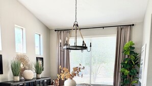 A dining area with a round table, chairs, a chandelier, and a potted plant. - Gorgeous Custom Home, Resort Amenities, Heated Pool, Stay in Luxury (Tempe)