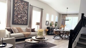 A modern living room with a sofa, coffee table, and dining area. - Gorgeous Custom Home, Resort Amenities, Heated Pool, Stay in Luxury (Tempe)