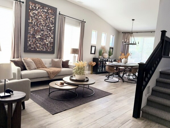 A modern living room with a sofa, coffee table, and dining area.